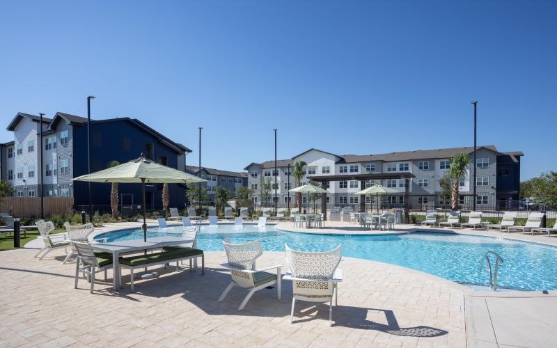 a pool with chairs and tables by it
