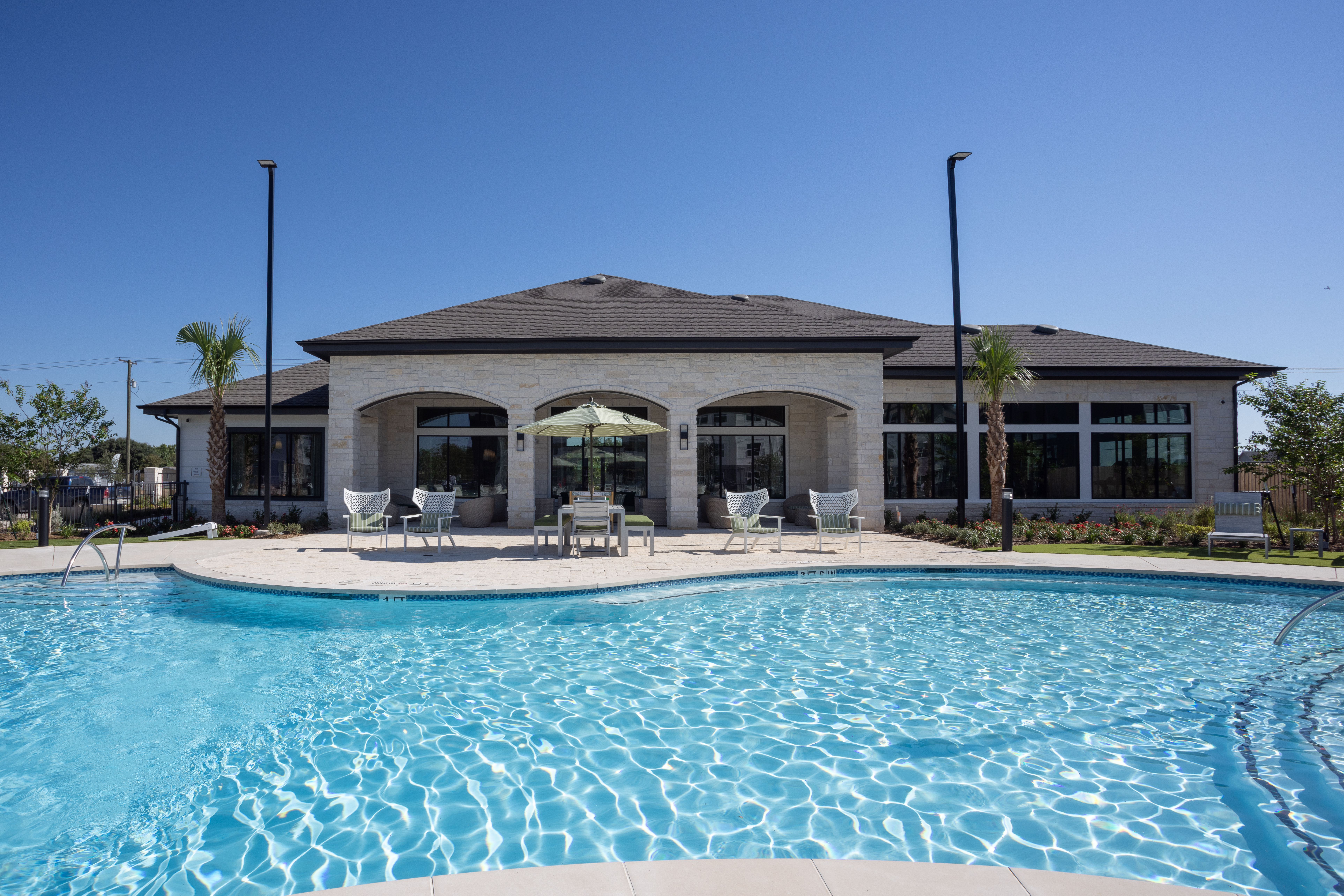 sparking blue pool with lounge chairs and tables around it with building exteriors behind at prose evergreen in new braunfels, tx