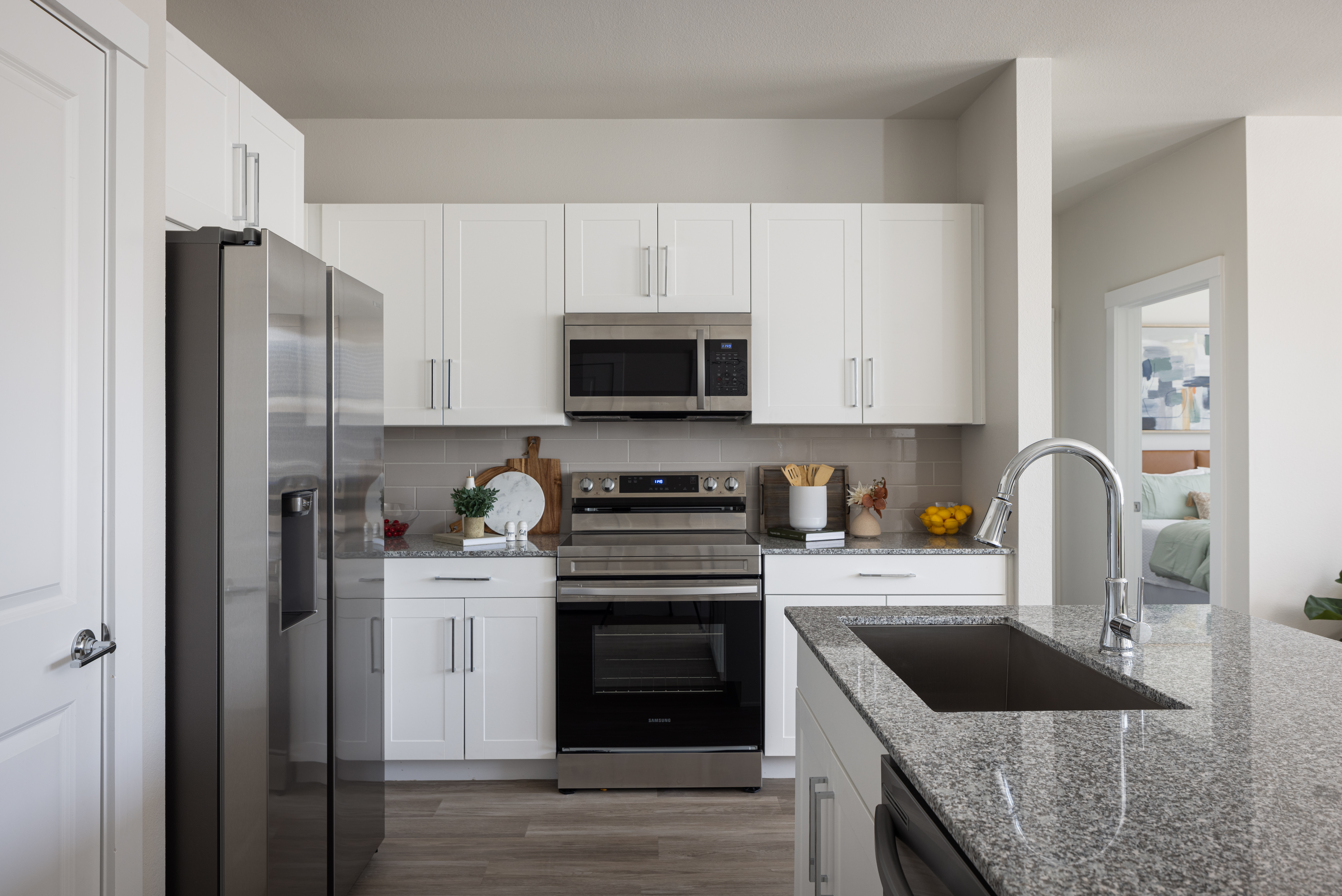 kitchen with white cabinets, grey countertop and chrome faucets with bartstool st the eat in bar at prose evergreen apts in new braunfels, texas