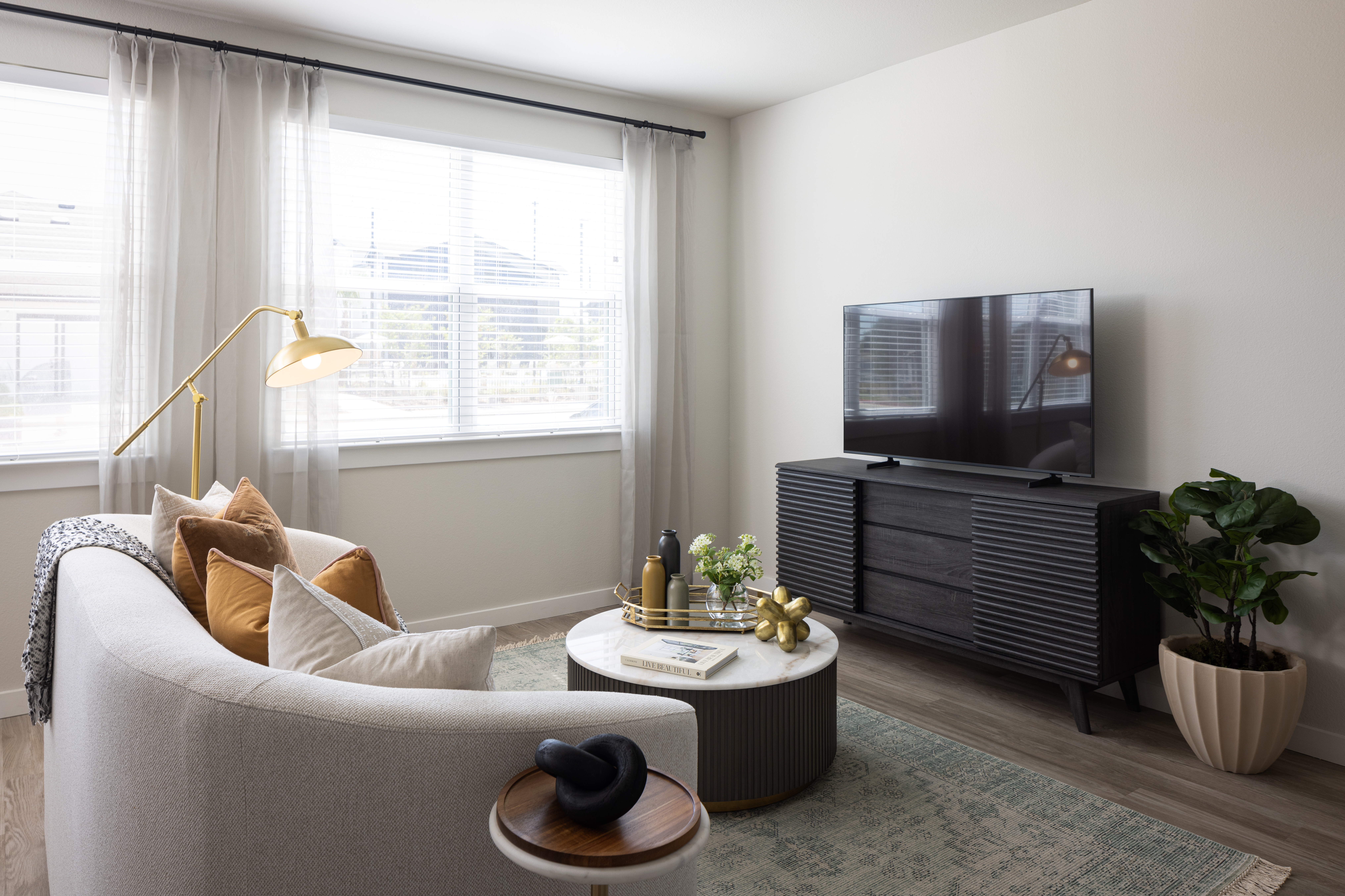 living room with round table in front, white couch in the middle and large painting on the wall in the back with two large bright windows at prose evergreen apts in new braunfels, texas