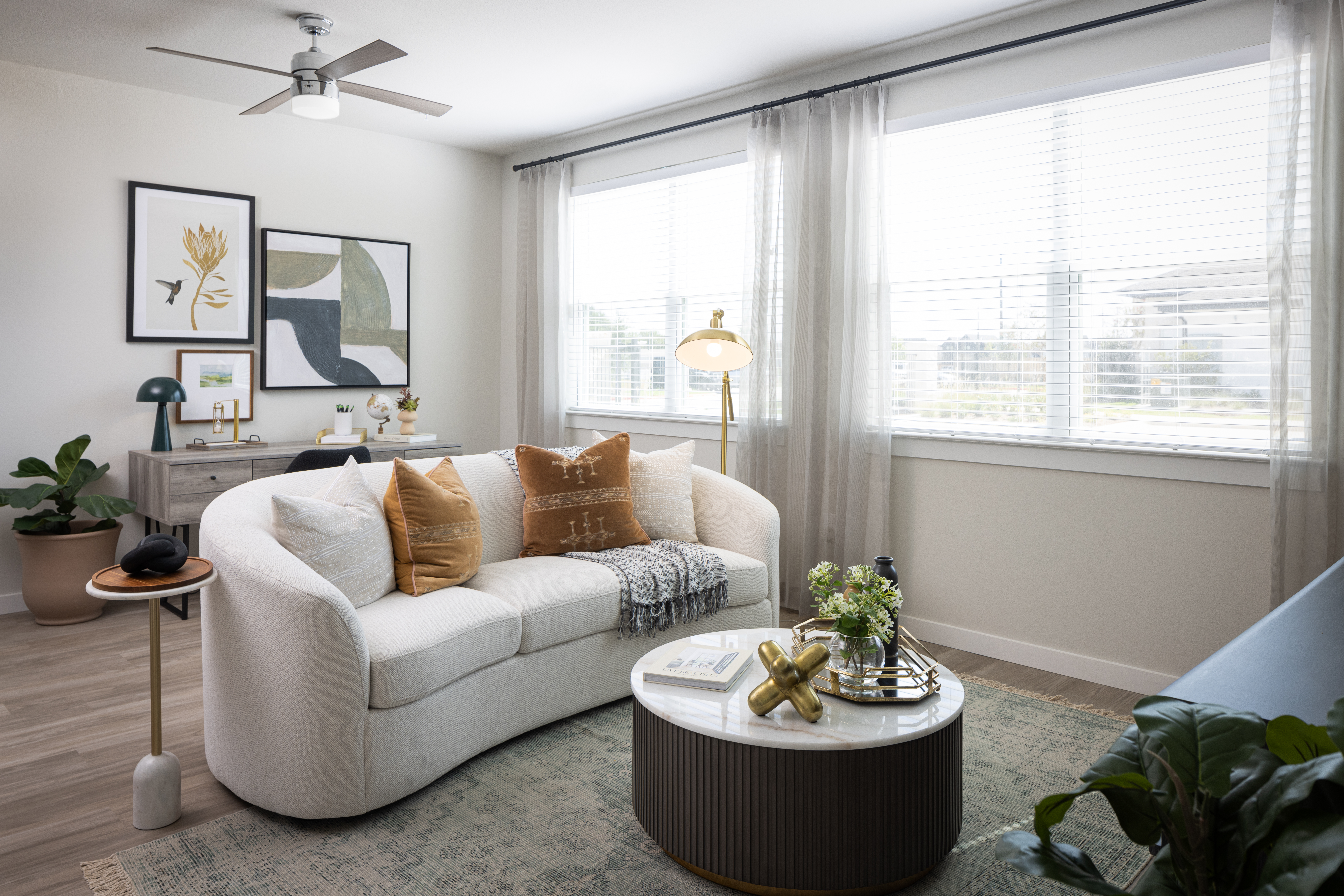 living room with round table in front, white couch in the middle and large painting on the wall in the back with two large bright windows at prose evergreen apts in new braunfels, texas