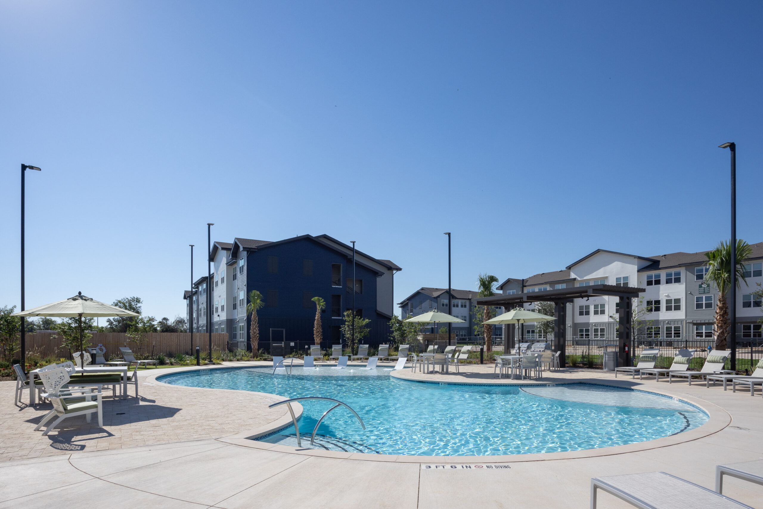 sparking blue pool with lounge chairs and tables around it with building exteriors behind at prose evergreen in new braunfels, tx