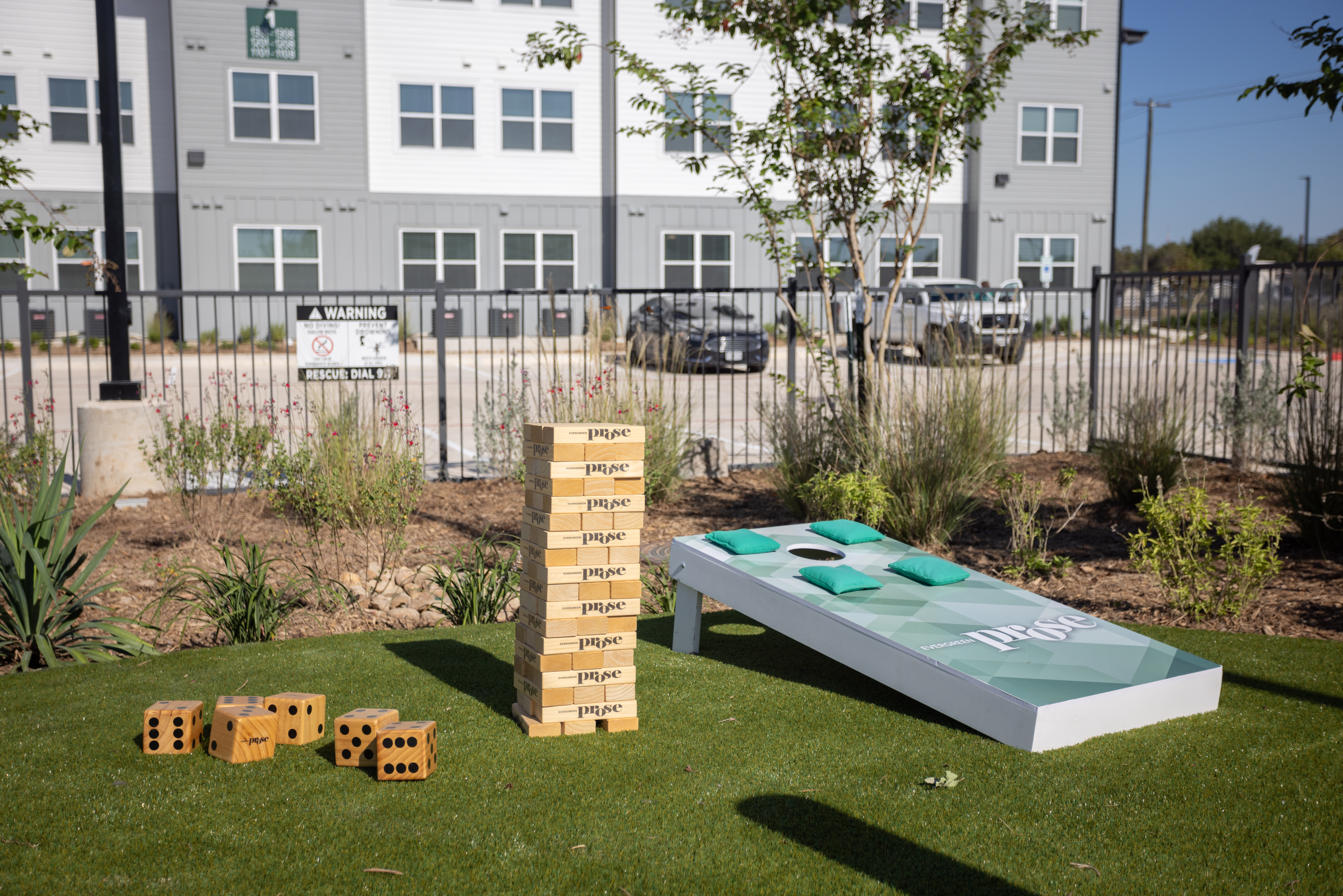 outdoor game at sparking blue pool with lounge chairs and tables around it with building exteriors behind at prose evergreen in new braunfels, tx